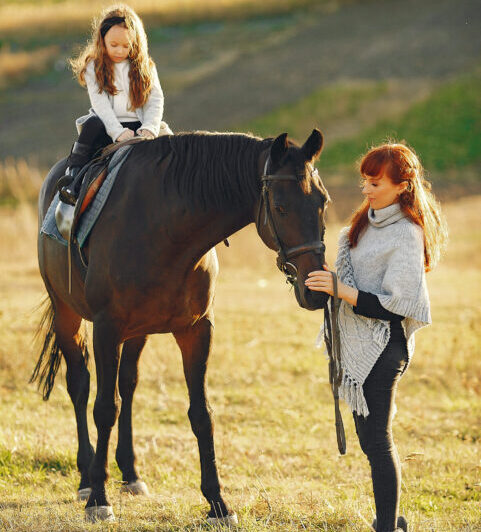 Mother and daughter in a field playing with a horse